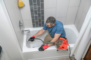Plombier en train de réparer une baignoire